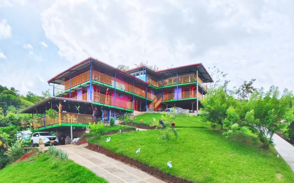 Fachada principal del Alojamiento Rural Las Madrigueras en Balboa, Risaralda, destacando su arquitectura colorida de varios niveles y amplios balcones con vista al Valle.