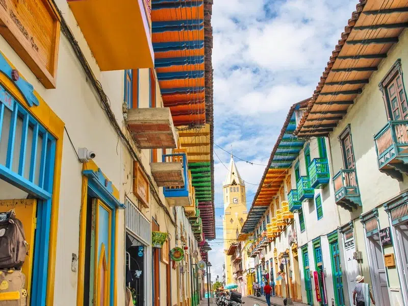 Calle real de Santuario, Risaralda, con casas de bahareque de colores vibrantes, balcones florecidos y arquitectura colonial antioqueña.