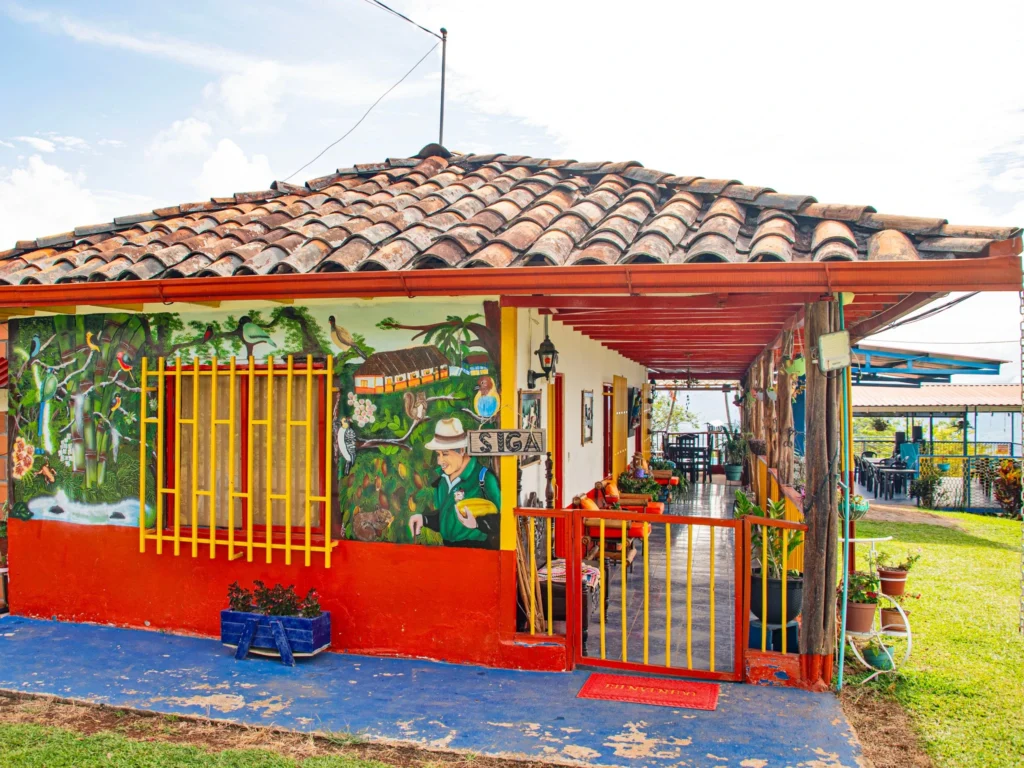 Fachada colorida de la Hacienda Vista Hermosa en Balboa, Risaralda, mostrando murales tradicionales, arquitectura cafetera y un mirador de montaña.