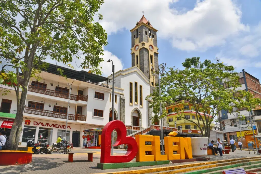 Plaza principal de Belén de Umbría en Risaralda con letrero turístico colorido y la torre de la iglesia de fondo.