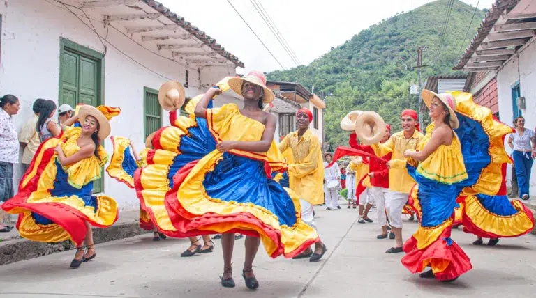 Grupo folclórico afrodescendiente bailando con trajes tradicionales amarillos y azules en una calle de Risaralda